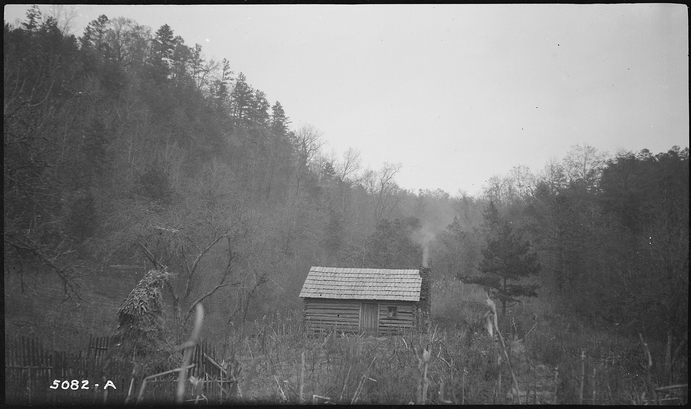 Smoke rising from the chimney of Fate Morrow's log cabin