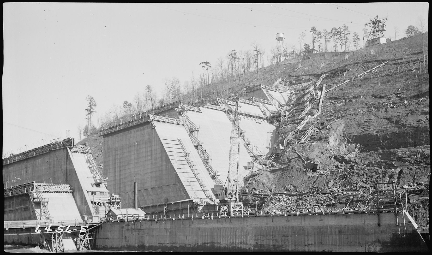 Hiwassee Dam rising across the river during construction, 1938