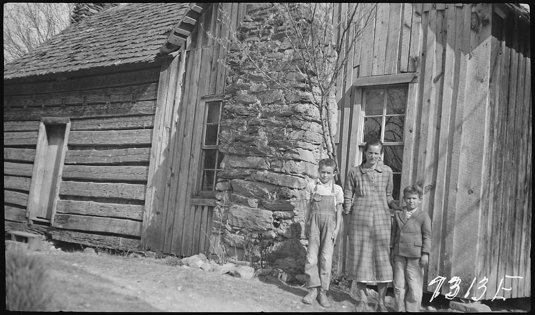 The Hogshed mother and children in front of their log and board home
