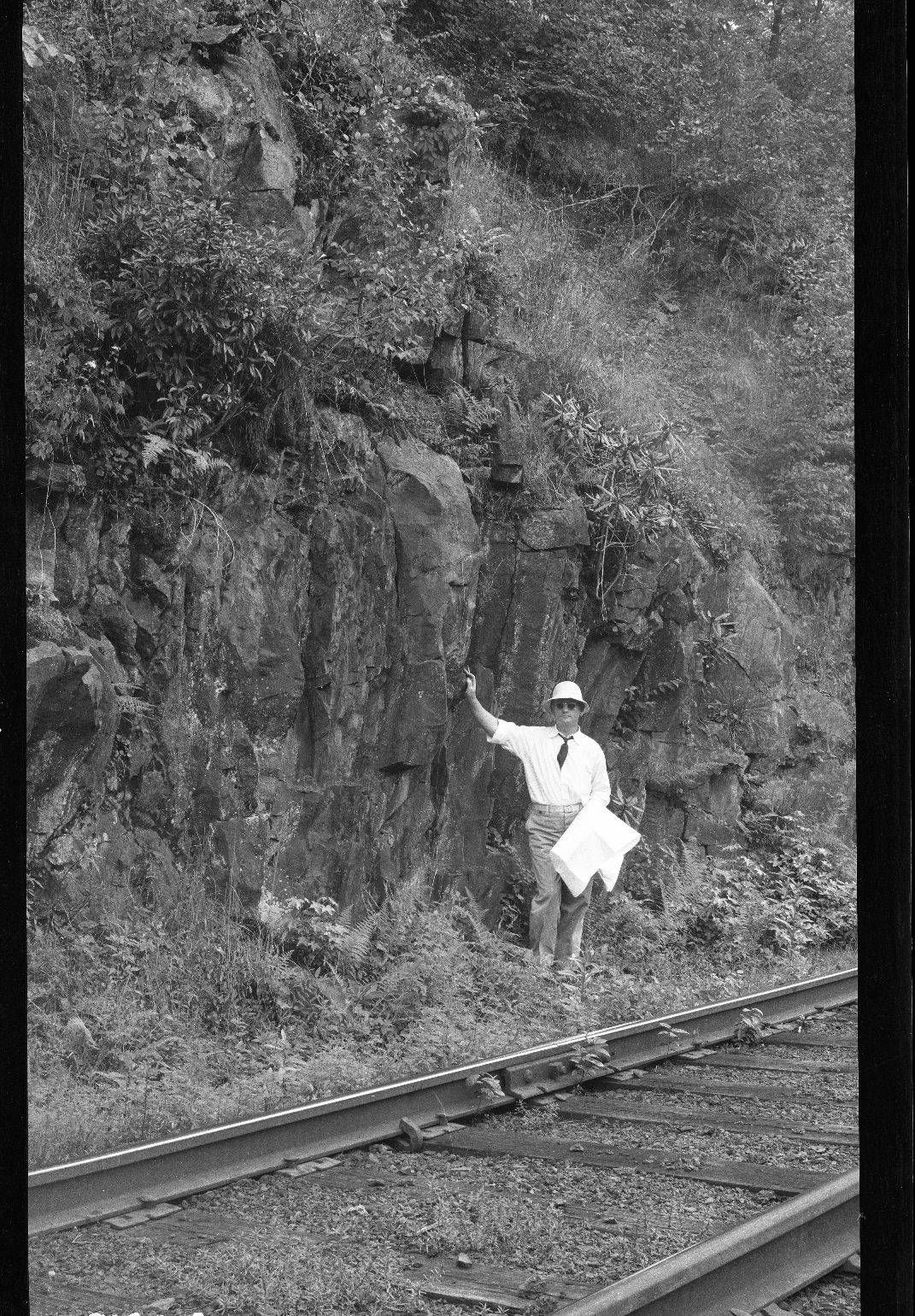 A man standing on the rock bank above the railroad below Apalachia station