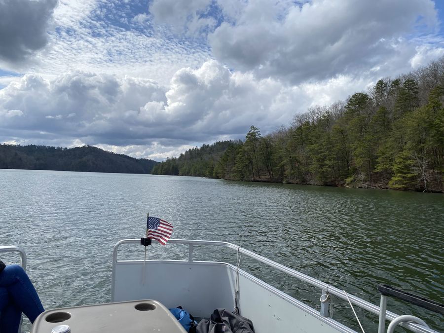 The lake from the front of a boat, with a small flag and a forested shore