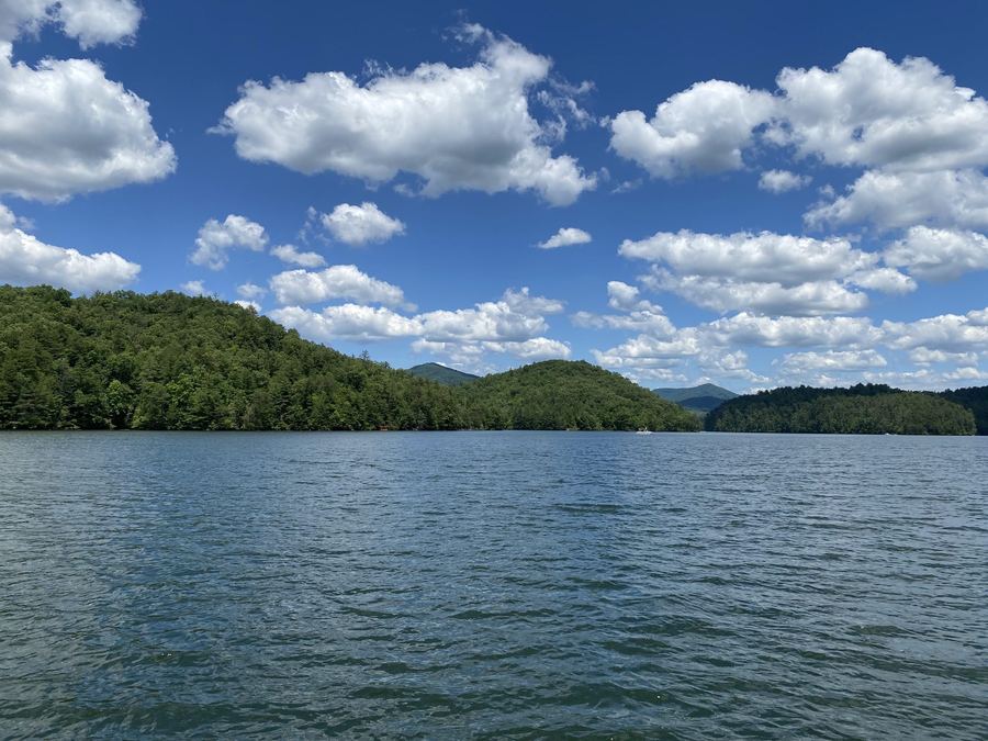 Open water with forested hills and white clouds
